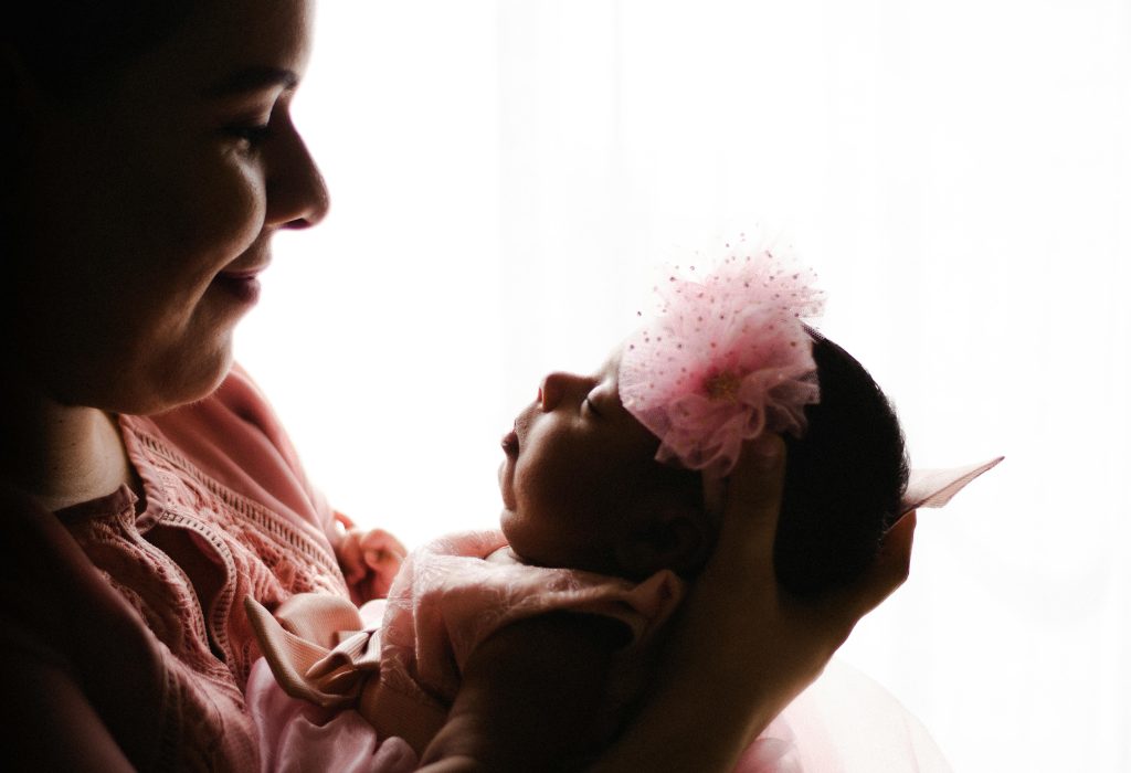 A mother lovingly cradling her newborn baby in soft, warm lighting.