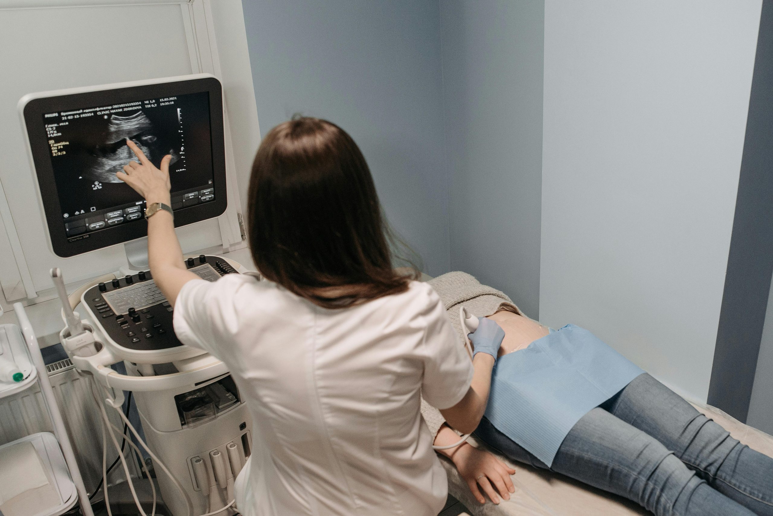 Female doctor conducting an ultrasound screening on a patient in a medical office.
